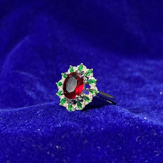 Ring with a red gemstone and green accents on a blue textured background